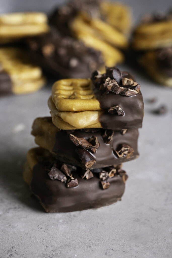 three Caramel Stuffed Chocolate Dipped Pretzels stacked on top of one another.