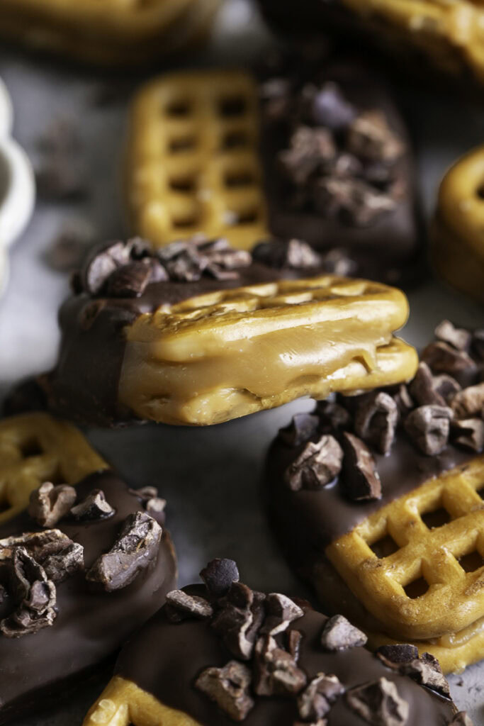 close up of Caramel Stuffed Chocolate Dipped Pretzels with caramel oozing out the side.