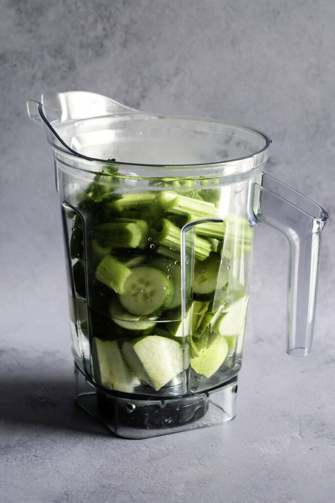 sliced celery, cucumber, green apple in a blender with water.