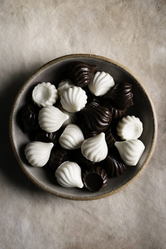 chocolate and white chocolate candy kisses piled on top of one another in a bowl.