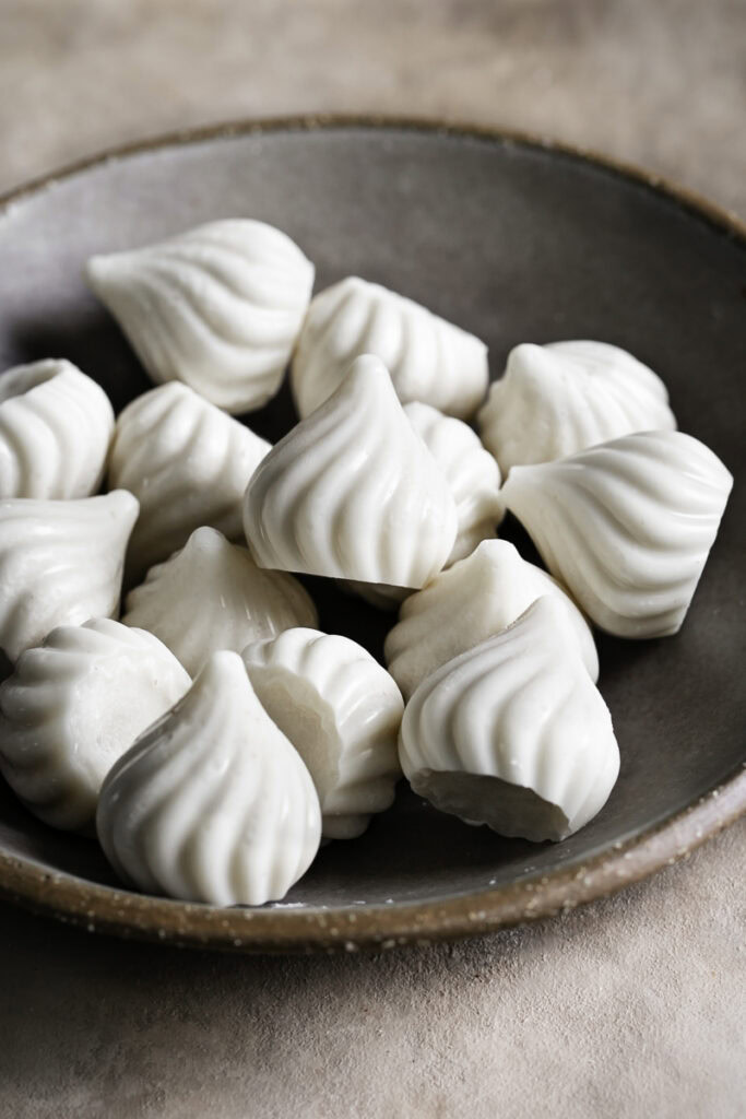 white chocolate candy kisses piled on top of one another in a bowl.
