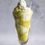 golden milk ice cream float in a tall glass with a glass straw.