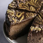 sliced vegan triple chocolate peanut butter cheesecake on a cake stand.